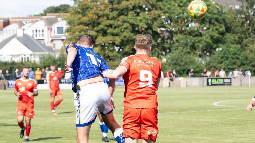Two footballers jumping to head the ball